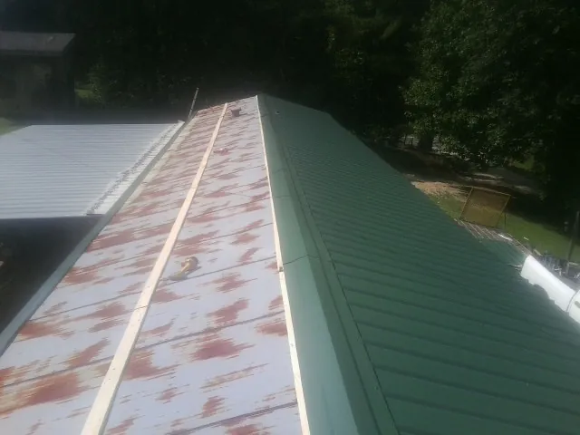 Old rusted panels beside newly installed green metal roofing — Wind Damage Roof Repair by Roofing Brothers in Tappan