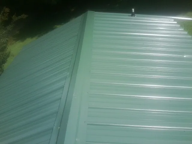 New green metal panels meeting at the ridge of a roof — Flat Roof Repair work by our crew in Tappan