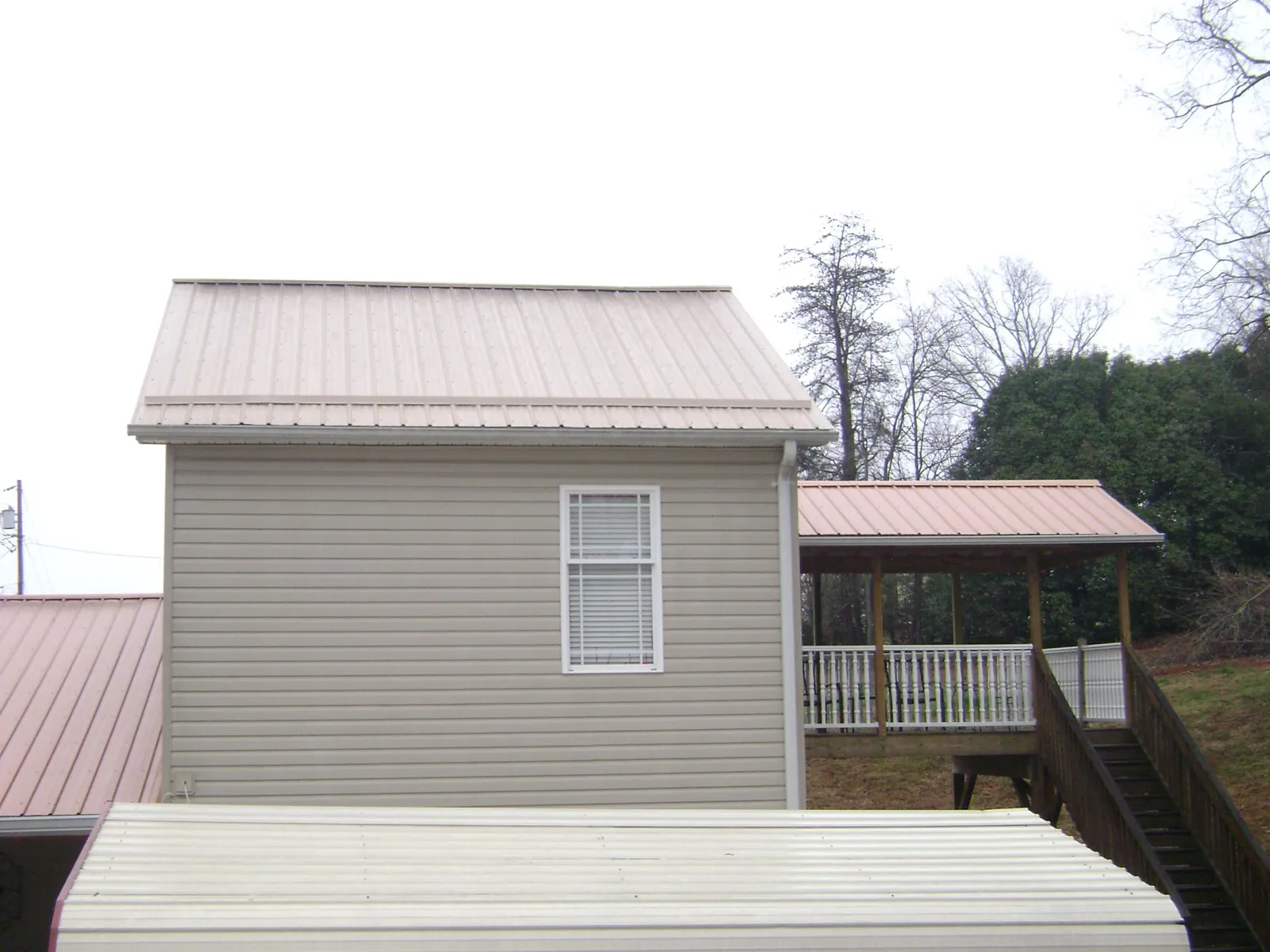 Tan metal roofs on a two story addition and attached porch, from a Roof Replacement job in Tappan