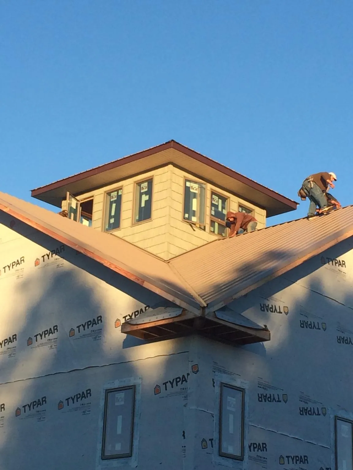 Roofers working around a rooftop cupola on a new metal roof at sunset — Roof Waterproofing in Tappan by Roofing Brothers